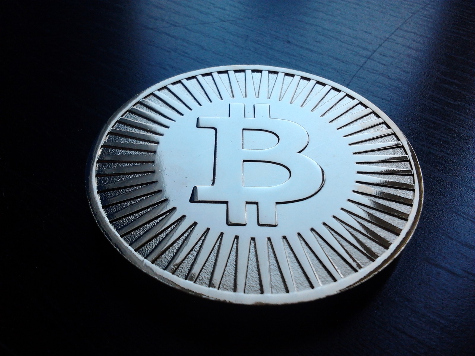 Photograph of a decorative physical coin bearing the Bitcoin symbol.